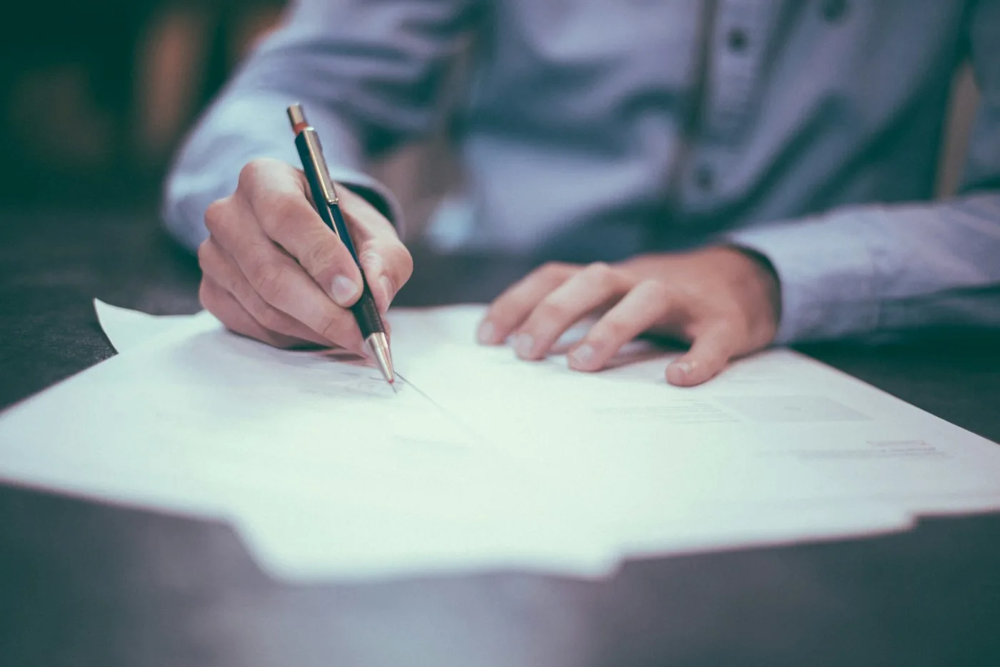 Close-up of a person writing on a paper document