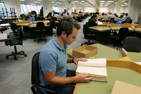 A researcher turning the pages of an original record in The National Archives reading room.