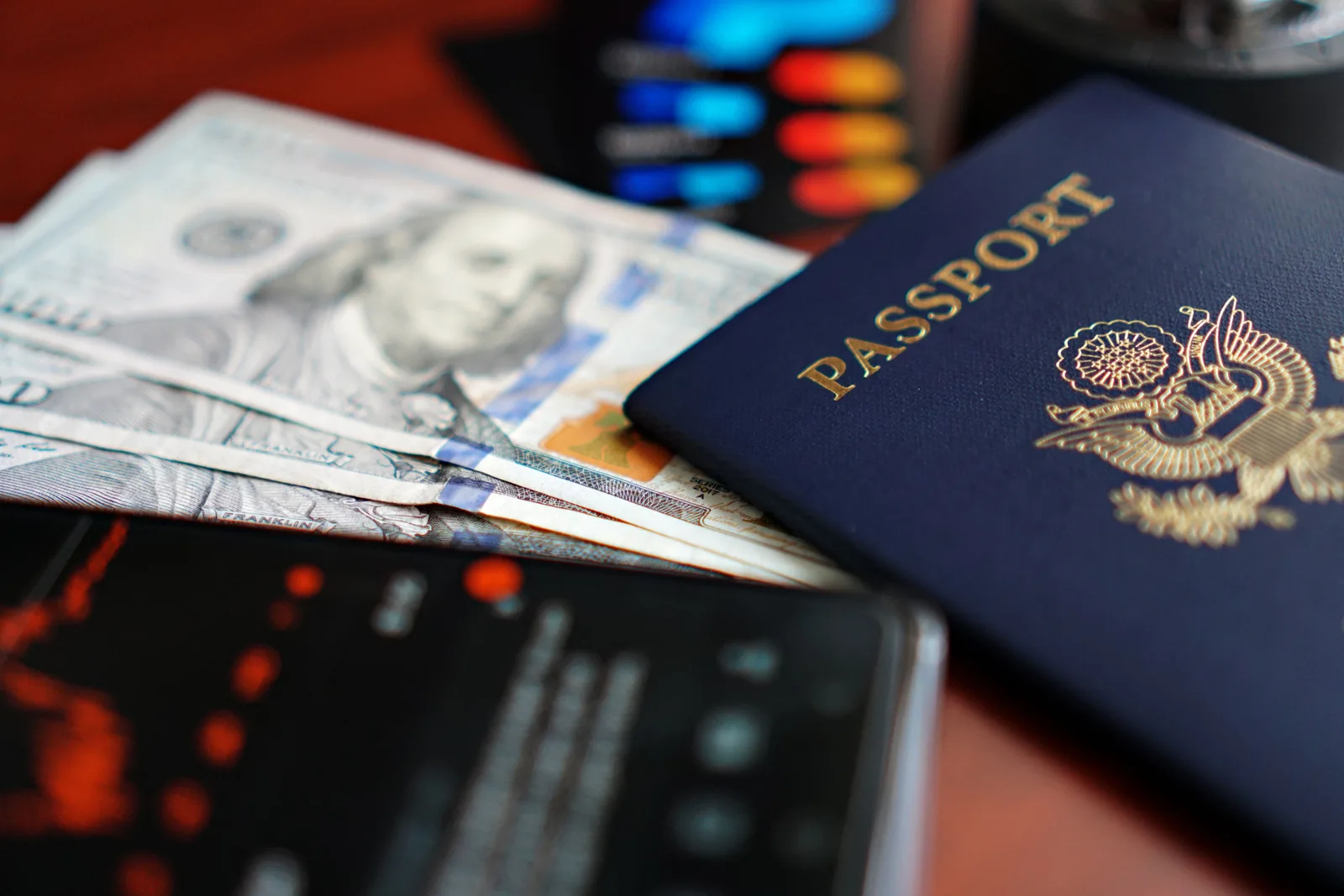 A U.S. passport rests beside U.S. dollar bills and a smartphone.