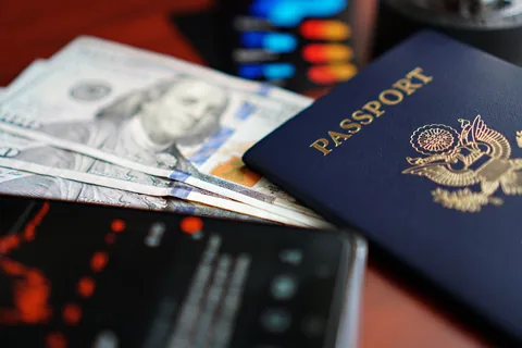 A U.S. passport rests beside U.S. dollar bills and a smartphone.