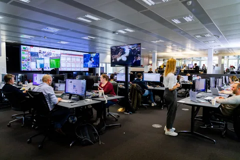 Journalists working at desks with computers and news monitors in the Blick newsroom in Zürich.